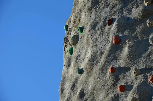 攀岩墙 由天然形状的人造石头制成 有不规则的间隔和螺丝状的石头 吊绳上用来固定攀登者的手柄和扣子 — 图库照片