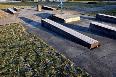 Parkta çizgili kompozisyon. Prizmatik şekilli katı kirişlerden yapılmış döşeme ve bankların şeritleri zemin kattaki süs çimleriyle eşit derecede kesişiyor. dinlenme yerleri taşlarla döşelidir.