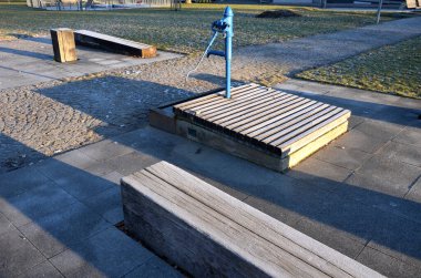 Parkta çizgili kompozisyon. Prizmatik şekilli katı kirişlerden yapılmış döşeme ve bankların şeritleri zemin kattaki süs çimleriyle eşit derecede kesişiyor. dinlenme yerleri taşlarla döşelidir.