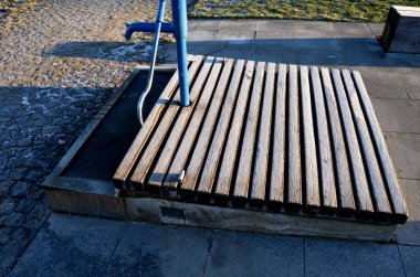 Mavi metal retro, parlak ahşap kapaklı. Su el pompasından taş yalağa akar. Bahçe tezgahı şekilli prizma çimenlik park mimarisi, dayanıklılık, ucuz