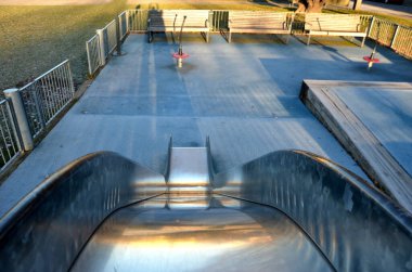 Paslanmaz çelik sürgülü oyun alanı, mavi kauçuk yüzey. Devasa kirişlerle çevrili teraslar. Kapısı köpeklere karşı olan galvanize çitler. Kırmızı salıncaklar çelik yay arka bahçesinde kreş plastiği