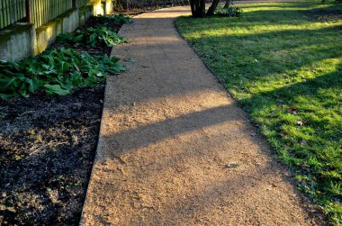 Yeni park harman yolunun çakıl taşlarını sıkıştırıyor. Çimen tohumu, suyla dolu metal bir el silindiri ile onarılırsa daha ağır olacaktır.