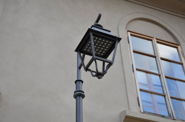 Tarihsel bir lamba tarzı. Bu gaz değil, LED ışıklar. Cam dolgu olmadan fener çerçevesi. Doğal cepheli, kahverengi kemerli ahşap pencereli tarihi şehir merkezi.