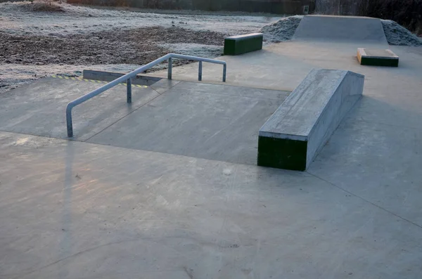 Skateboard park with concrete cement surface with concrete skateboard obstacles is designed for roller sports. Cycling is not allowed except for freestyle bikes. icing winter morning sunrise