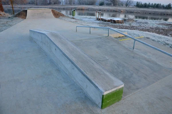 Skateboard park with concrete cement surface with concrete skateboard obstacles is designed for roller sports. Cycling is not allowed except for freestyle bikes. icing winter morning sunrise