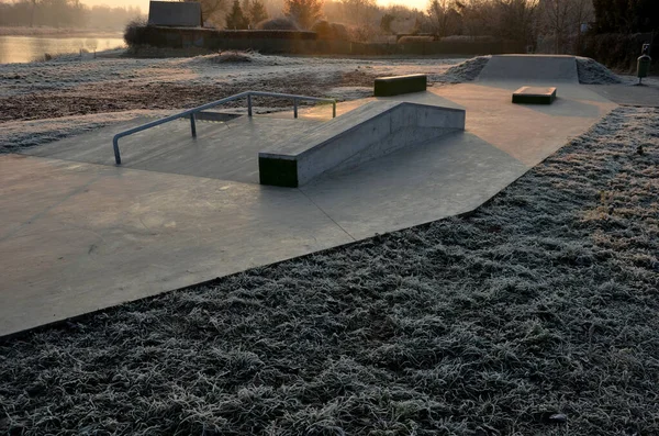 Skateboard park with concrete cement surface with concrete skateboard obstacles is designed for roller sports. Cycling is not allowed except for freestyle bikes. icing winter morning sunrise