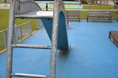 Paslanmaz çelik sürgülü oyun alanı, mavi kauçuk yüzey. Devasa kirişlerle çevrili teraslar. Kapısı köpeklere karşı olan galvanize çitler. Kırmızı salıncaklar çelik yay arka bahçesinde kreş plastiği