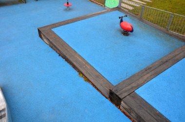 Paslanmaz çelik sürgülü oyun alanı, mavi kauçuk yüzey. Devasa kirişlerle çevrili teraslar. Kapısı köpeklere karşı olan galvanize çitler. Kırmızı salıncaklar çelik yay arka bahçesinde kreş plastiği