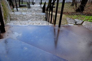 Yığılmış taşların yolu, kırmızı tuğlalar dizilmiş. Yanmış tuğlalar köprünün altındaki yamacı güçlendirir. Sabahın erken saatlerinde. kaba dokular asfaltlanıyor