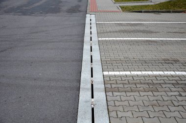 Birbirine kenetlenmiş beton oluklardaki drenaj elementleri tek bir beton parçasından dökülen su, park alanındaki suyu tüm avlu boyunca tutabilir.