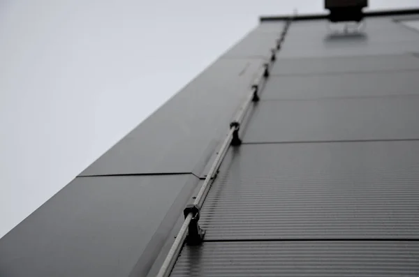 雷導体は 家や工業ホールを損傷する可能性のある雷から建物を保護するために使用されます 灰色の金属板のファサードに沿って配線を接地 プラスチックホルダー — ストック写真