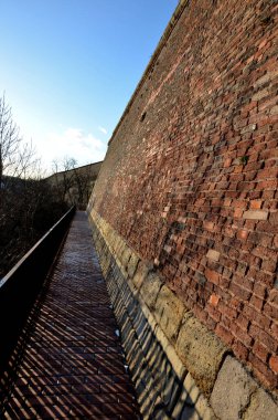 Barok Kalesi 'nin yanındaki yol. Korse metalinden yapılma modern parmaklıklar. Kaldırımlar yanmış tuğlalarla döşelidir. Duvarların yüksek duvarı topçu mermilerini yukarı yansıtmak için eğimli.