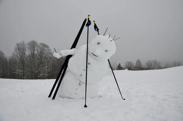 The big snowman has a tilted body that looks like he\'s falling. has ski poles and cross-country skis. jumping mascot. slow melting andfreezing tilts the center of gravity