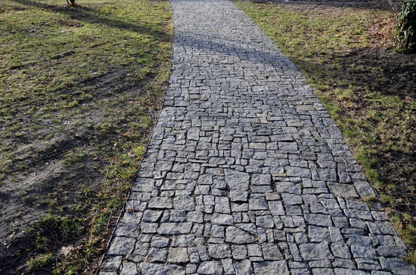 connecting the park path and sidewalk to the asphalt road using a strip of concrete blocks with protrusions for the blind. they know where the sidewalk ends with the mass of feet. drainage tiles soak up rain water