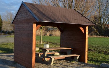 Nehir asfalt yolunun kenarında, bisiklet yolunun gittiği yerde. İlk gezgin, bisiklet turuna eğildi. Spor salonu beton pergola yakınında yuvarlak pencereli, kırmızı motorlu, kremalı, sabah