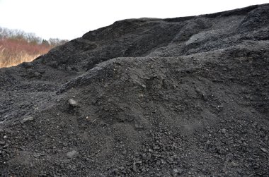 Çöp sahasında büyük bir yığın üzerinde yol değirmeninden geri dönüştürülmüş asfalt. Kazı kaşığından alınan bir şeyin izleri. Rengi ve yapısı bir kömür madenine benziyor. İnşaat atıklarının ekolojik kazanımı