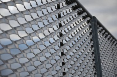 Genişletilmiş metal levha eskrimi. Galvanize parmaklıklardan yapılmış çok dayanıklı parmaklıklar. Süslü otların şeridi mekana insafsız bir bakış kazandırıyor. Öğütücü olarak yarı saydam