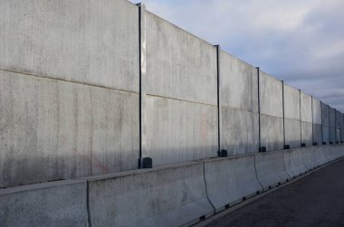Ses geçirmez duvar, beton, gözenekli tırtıklı malzemeden yapılmış. Metal kirişlere gömülmüş gri bloklardan oluşan bir çit. Trafik gürültüsü bahçesi ve yerleşim alanı. Kudüs 'ün korunması, roket