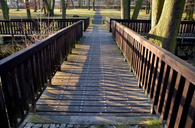 Köprüler ve yaya köprüler doğal peyzaj için iyi bir eklenti. Nehir geçidinde parmaklıkları olan gözlem güvertesi. Çakıl ve granit mozaiklerin yolları.