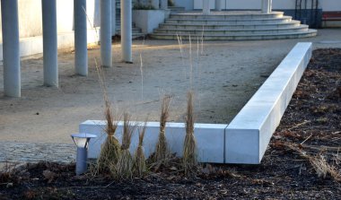 Atari salonlarının ve beton bankların olduğu avluda kış için korunmak üzere biberiyeli ve süs otlu bitkiler var. sütunlu kare ve merdiven