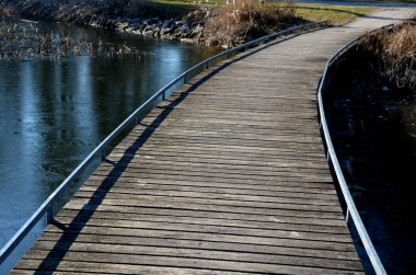 Tahta kalaslardan, rıhtımdan, göl suyunun dibine kadar uzanan cambaz ayaklıklarının üzerindeki dar kıvrımlı patikalardan oluşan yüzen yürüyüş yolu. Korkulukları yok. Tekerlekli sandalyeler için daha çok korkuluklu kaldırım
