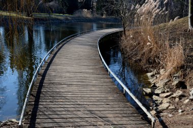 Tahta kalaslardan, rıhtımdan, göl suyunun dibine kadar uzanan cambaz ayaklıklarının üzerindeki dar kıvrımlı patikalardan oluşan yüzen yürüyüş yolu. Korkulukları yok. Tekerlekli sandalyeler için daha çok korkuluklu kaldırım