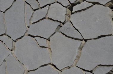 Betondan yapılma düzensiz şekilli kaldırım taşı. Çatlak kuru toprak deseni drenaj kaldırımı olarak ya da otla birlikte kullanılabilir.