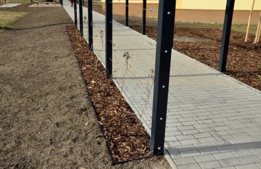 Otobüs durağının metal inşaatı, çardak pergola barınağı. Çatı ve duvarlar tırmanma tesisleri için bir halat ağıyla örülmüş. Paslanmaz çelik eşleşmelerle sabitlenmiş. siyah blok şekilli tünel,