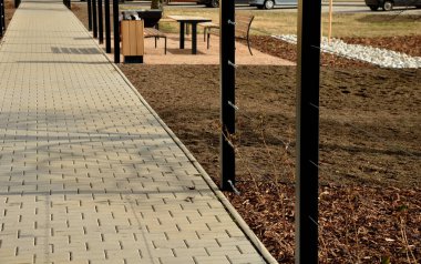 Otobüs durağının metal inşaatı, çardak pergola barınağı. Çatı ve duvarlar tırmanma tesisleri için bir halat ağıyla örülmüş. Paslanmaz çelik eşleşmelerle sabitlenmiş. siyah blok şekilli tünel,