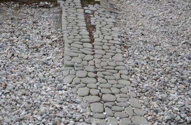 Çakıl taşlarıyla dolu delikleri olan normal bir ızgaradaki havalanmış beton fayanslardan yapılmış yeni sızma otoparkı. Birbirine kenetlenmiş kaldırımlar, kaya desenleri, çakıl taşları.