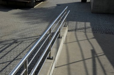 İki tırabzanla korkuluk. Galvanize çelik prizmalardan yapılmış. Alt korkuluk tekerlekli sandalyelere karşı bir koruma sağlar. Konutlardaki hareketsizler için rampa, paslanmaz çelik, merdiven, rampa.