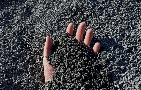 a man\'s hand buried in an accident that brings earthquakes or mining accidents. in fine gravel which is used for park construction of roads. fingers covered with sand in a pile dumped by a truck