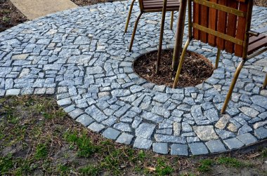 Ortasında bir delik olan yuvarlak masa bir dikim ağacıdır. Bir kafenin önündeki bahçe mobilyaları. Pirinç masa ve sandalye çerçevesi şehrin parkında ahşap ile birleştirilmiş..