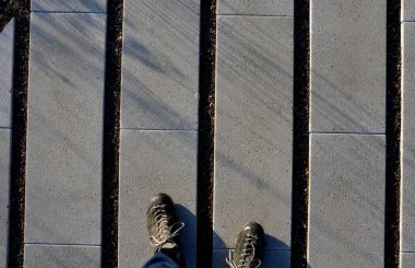 Çizgilerinde boşluklar olan beton gri fayanslar. Çimenler boşluklarda yetişir ve otoparkın ya da kaldırımın içine sızma yüzeyi görevi görür. ekolojik kaldırım