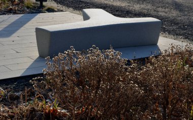 Meydanda yapay taştan yapılmış gri, beyaz bir bank duruyor. T ya da Y şeklinde beton döküm. Kışın ebedi çiçek yatakları sabah güneşinde donla kaplıdır..