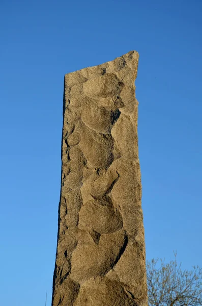 花崗岩の柱は珪藻化石の槍の先史時代の生産を思わせる粗いチップで石打ちされている 灰色の石の青い空 記念碑や墓石 — ストック写真