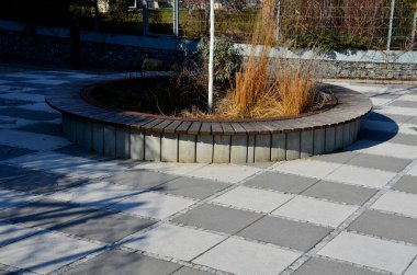 Ağacın gövdesini çevreleyen daha küçük tahtalardan oluşan yuvarlak banklarla çevrelenmiş, yerden yükseltilmiş ağaç kaseleri. Çiçek saksısı uzun yıllıklarla ekilir.