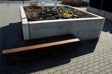 Parka bakan teras, köşesinde ahşap bir bank olan beton uzun, monolitik kare bir saksıdan oluşuyor. Caddedeki ve meydandaki şehir avlusunun bir parçası. İçinde süs otları ve bir ağaç vardır.