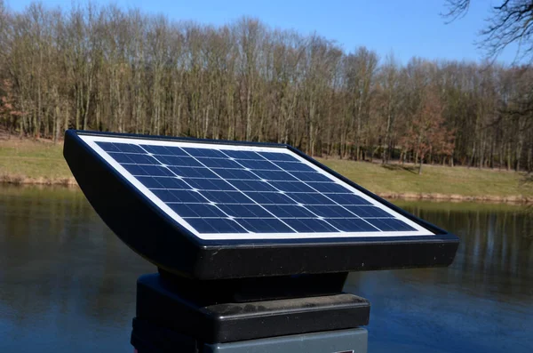 black solar panel by the river embankment. used to charge a parking meter, information interactive screen, traffic radar and other city equipment.