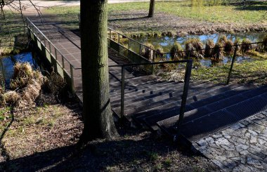 Paslı örgü levha metalden yapılmış bir köprü. Genişletilmiş metalden yapılmış tırabzanı olan şeffaf bir metal levha. Geniş park köprüsü yamaçta merdivenlerle bataklığın üzerinde.