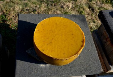 Paslanmaz çelik buhar kazanında hastalıklarla dolu eski siyah balmumu tarakları eriten bir arıcının işi. Arı kovanında büyük bir balmumu pastası. Satılık birkaç kilosu var, balmumu fiyatları artıyor.