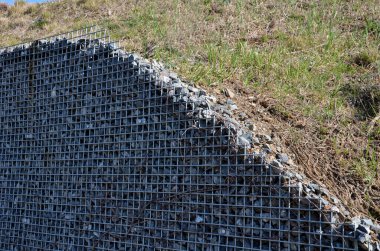 Gabion büyük istinat duvarı, sepet doldurulmuş ve taşla kaplanmış. Suyu filtrelemek ve aynı zamanda erozyona karşı koymak için hindistan cevizi jütüsüyle doludur. Tren raylarının altındaki jeotextil 'ler. banka
