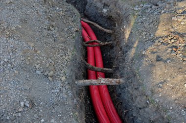 Yere yüksek voltaj kabloları döşüyordu. Çevre elektrik direklerine zarar vermez. Yerdeki kazı metresi güçlü kablolar ile kaplı kırmızı plastik kaplama. Saygılı bir şekilde Tree Ro 'dan geçer.