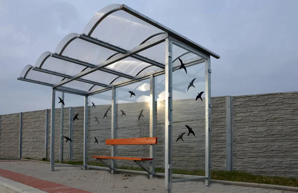市内バス停 統合された木製のベンチとガラス小屋 屋根と後ろの壁だけだ エレガントなアーチ屋根バスステーションプラットフォーム 壁に鳥のシルエットを接着してガラスに当たり — ストック写真
