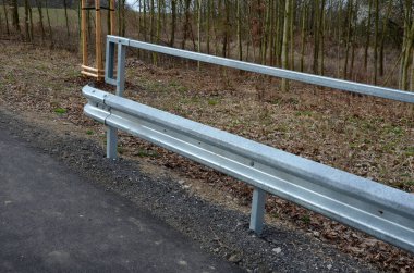 Asfalt yüzeyi olan bisikletçilerin yolu. yol bariyerlerinden geçen galvanize demir parmaklıklar. Kenarlara eğimli bir köprü korkuluğu. Parmaklıklar, üçgen şeklinde delinmiş metalden yapılmıştır.