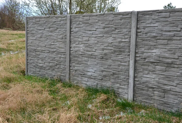 fencing with a gray panel fence in the garden with a lawn and concrete interlocking paving. A panel fence is the best protection against noise and creates privacy against neighbors and sneakers