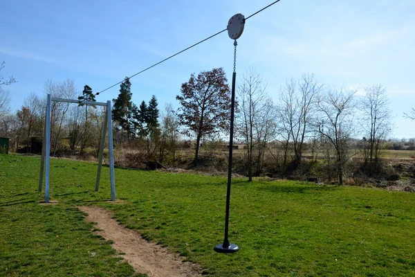 cable car for children on the playground. the child sits hung on a rope and goes downhill on a pulley on a stretched rope, cable car. a grassy meadow with two gates and a hill from which to start
