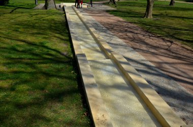 Parkta gezinti, yamaçtaki batık bir çukurda yapay bir akıntı. Su pompanın içinden yukarı aşağı akar ve şelaleler merdivenlerden taşar. bej gölet ve ahşap köprü