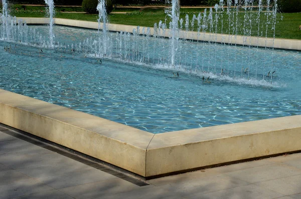 Parkta gezinti, olukta yapay akış. Fıskiyeler, fıskiyeler, fıskiyeler, fıskiyeler. mavi klorlu suyla bej gölet