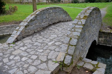 Kemer köprüsü, kemere demiryolu döşenmiş taş granit. İngiliz peyzaj parkı. Derenin çimenli hendeği küçük atlama kanalını geçer. Hendekler arazide su tutarlar